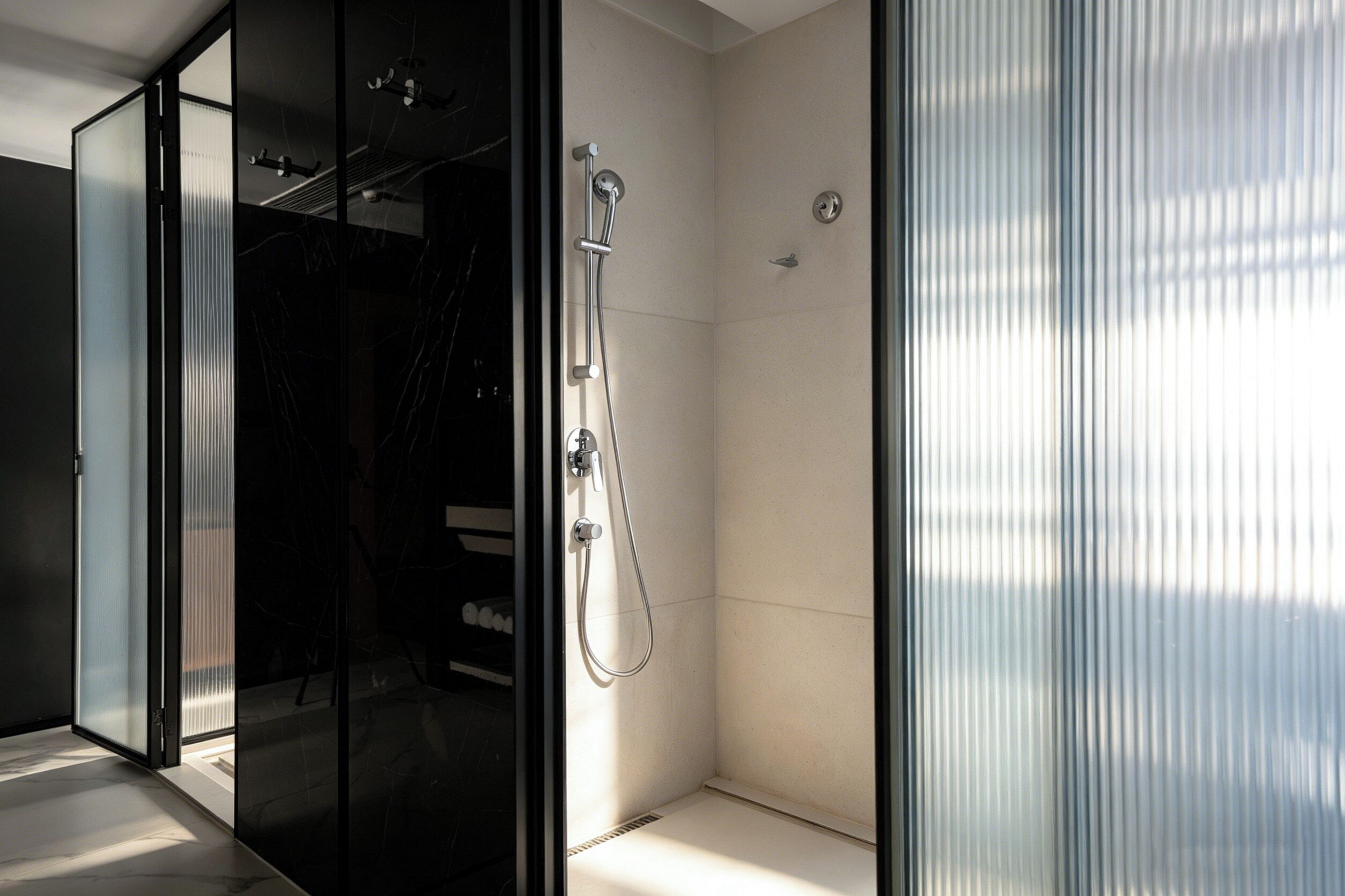 Ein modernes Badezimmer mit einer Duschkabine aus Glas, einer sichtbaren Dusche und einem gefliesten Boden.