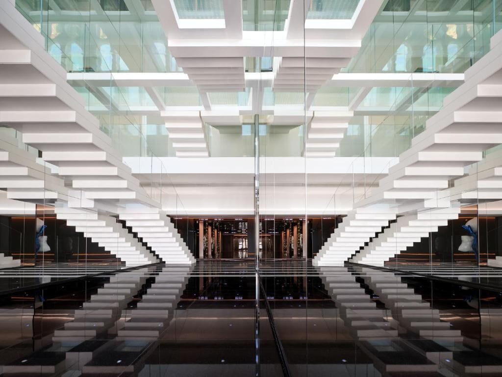 A modern building with a symmetrical design, featuring a central glass facade and a series of white, geometric structures.