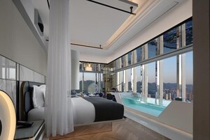 Un dormitorio moderno con un ventanal grande, una cama, una mesita de noche y vistas a la ciudad.