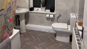 A bathroom with a window, a sink, a toilet, and a radiator. - Modern Nextdoor Stays (Morden)
