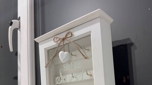 A white decorative window frame with a heart-shaped ornament and the words "HOME SWEET HOME" on a frosted glass panel. - Modern Nextdoor Stays (Morden)