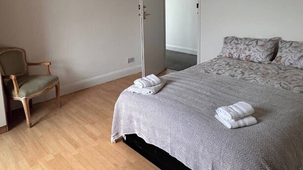 A bedroom with a bed, a chair, and a wardrobe. - Modern Nextdoor Stays (Morden)