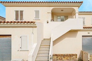 Un bâtiment doté d’un escalier menant à un balcon, d’une porte de garage et d’un mur en pierre.