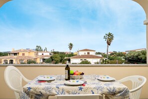 Ein Balkon mit Esstisch, einer Weinflasche und Obstschale.