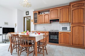 Une cuisine avec des meubles de rangement en bois, un four à micro-ondes et une table à manger avec des chaises.