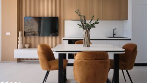 Una cucina moderna con una TV, un vaso con piante verdi e due sedie.