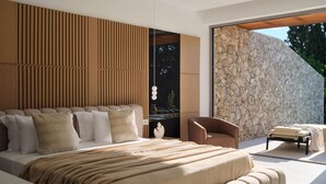 Una camera da letto moderna con un letto grande, un'area salotto e un muro in pietra.