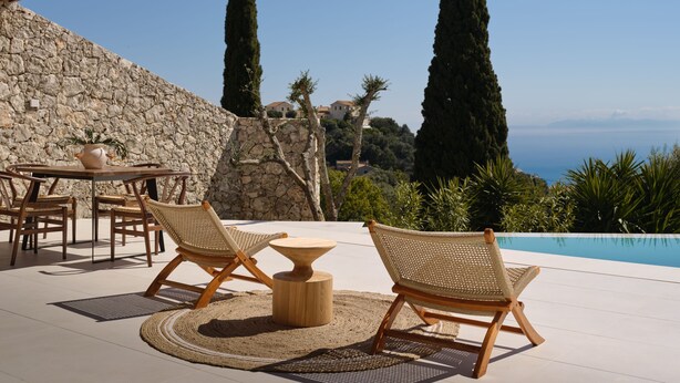Un patio con due poltrone in vimini, un tavolo e un tavolino rotondo.
