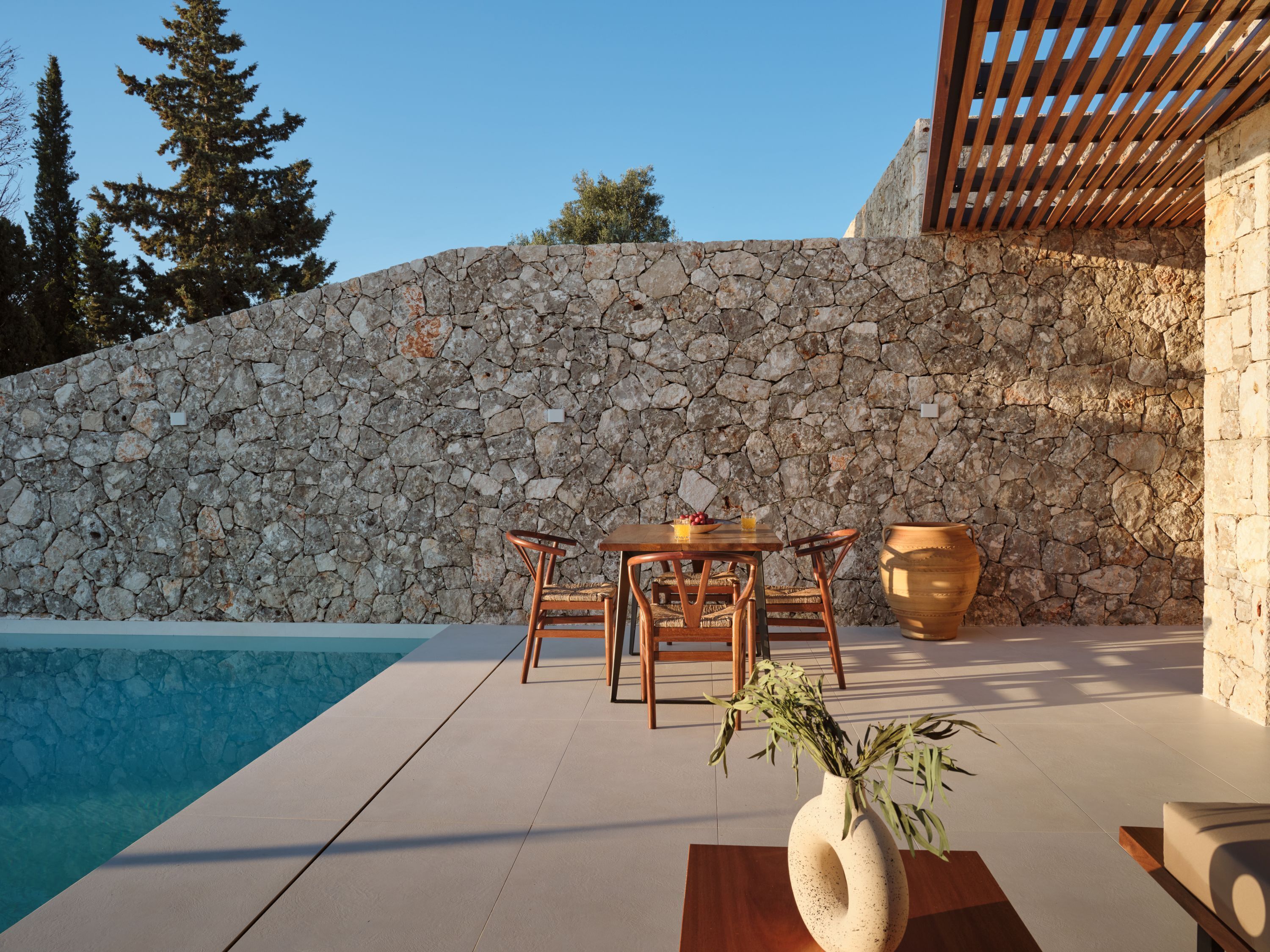A stone wall, a pool, and outdoor furniture.