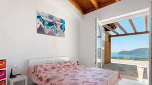 Une chambre à coucher avec un lit, une table de chevet, une lampe et une vue sur la mer.
