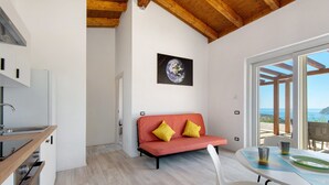 Une cuisine moderne avec des meubles blancs et un plan de travail en bois, un canapé rouge avec des coussins jaunes et une table à manger avec des chaises.