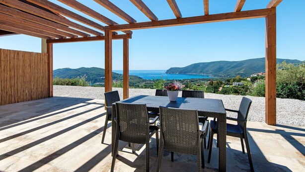 Un espace extérieur abrité, avec une table et des chaises, offrant une vue sur un paysage pittoresque.