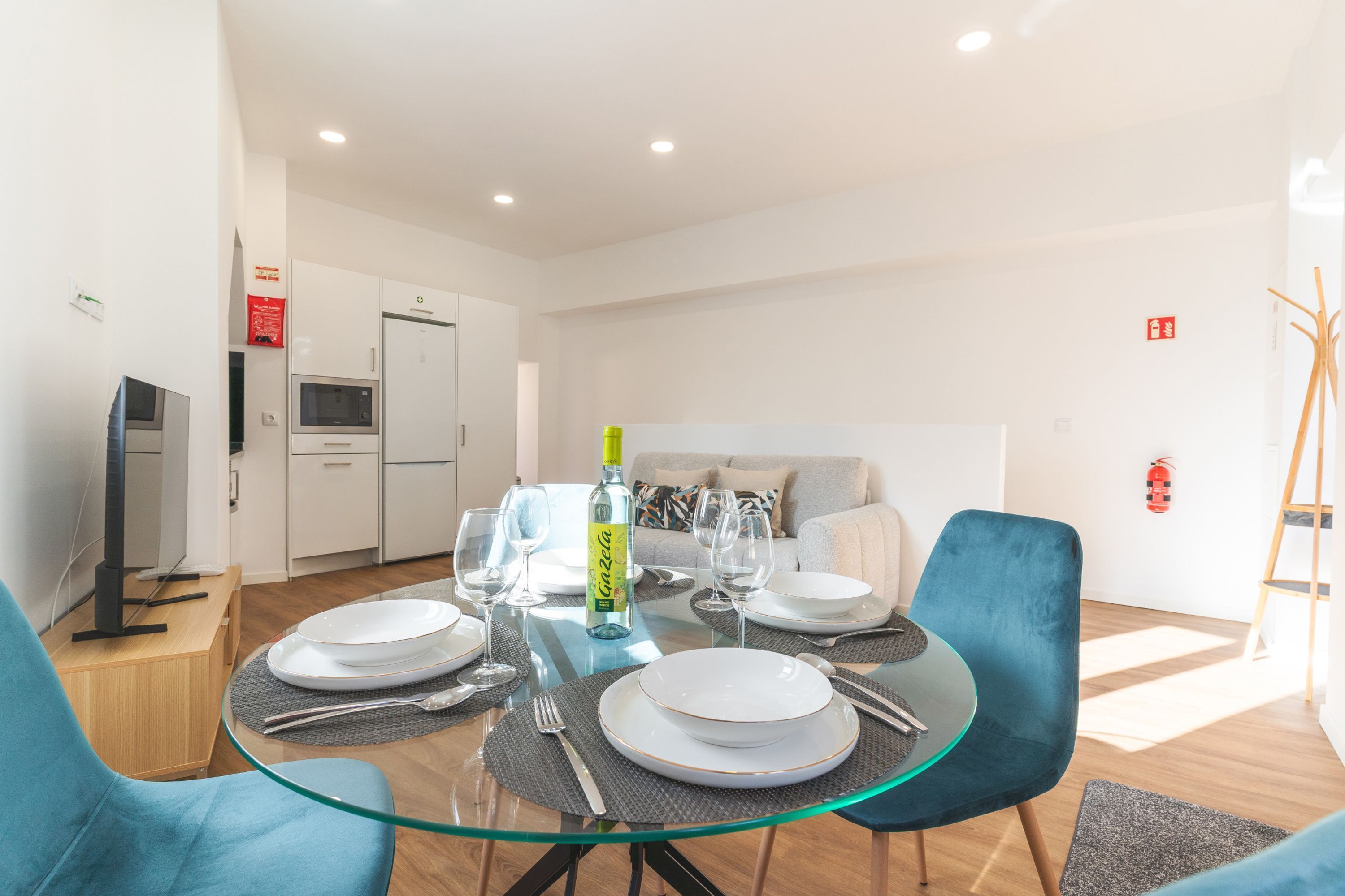 A modern dining area with a glass table, blue chairs, and white plates.