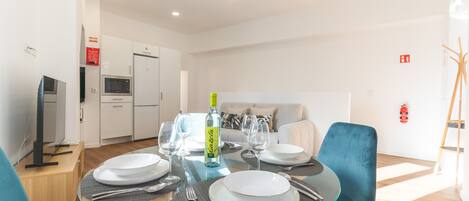 A modern dining area with a glass table, blue chairs, and white plates.