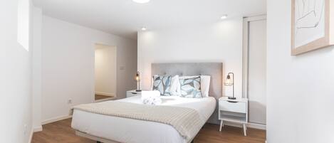 Un dormitorio moderno con una cama grande, mesitas de noche y cabecera.