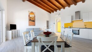 A modern kitchen with white cabinets, a yellow accent wall, and a wooden ceiling. - Adriana Trilocale Apartment with Sea View and Wi-Fi (Lacona)