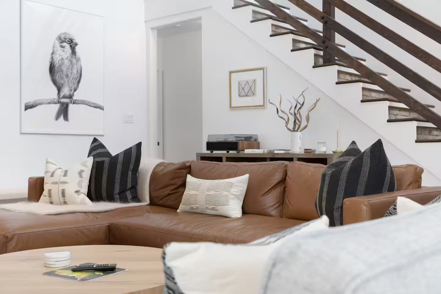 A modern living room with a brown leather sofa, a coffee table, and a framed artwork of a bird on the wall.