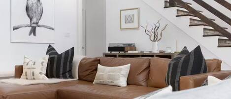 A modern living room with a brown leather sofa, a coffee table, and a framed artwork of a bird on the wall.