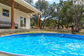 A swimming pool with a wooden deck and a covered patio area.