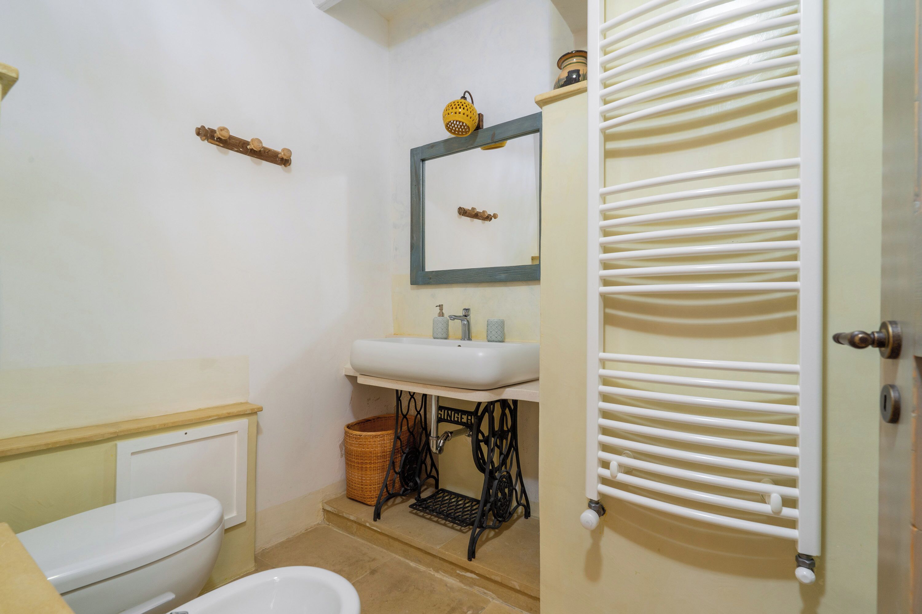 A bathroom with a white toilet, a sink with a mirror above it, and a radiator.