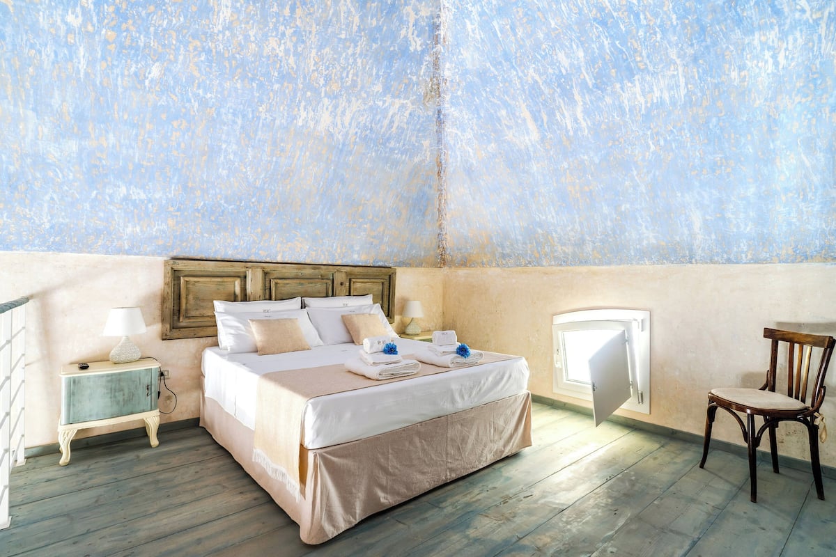 A bedroom with a bed, bedside tables, a chair, and a window.