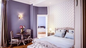 Une chambre à coucher avec un grand lit, une petite table avec des chaises et une table de chevet avec une lampe.
