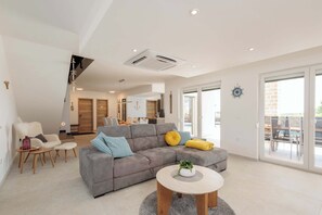 A modern living room with a grey sectional sofa, a round coffee table, and a dining area with a glass door leading outside. - Villa Farini - with private pool near Porec (Farini)