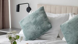 A neatly made bed with a beige headboard, a bedside lamp, and two matching pillows. - Air Condtioned Apartment | Rooftop Pool (Mielno)
