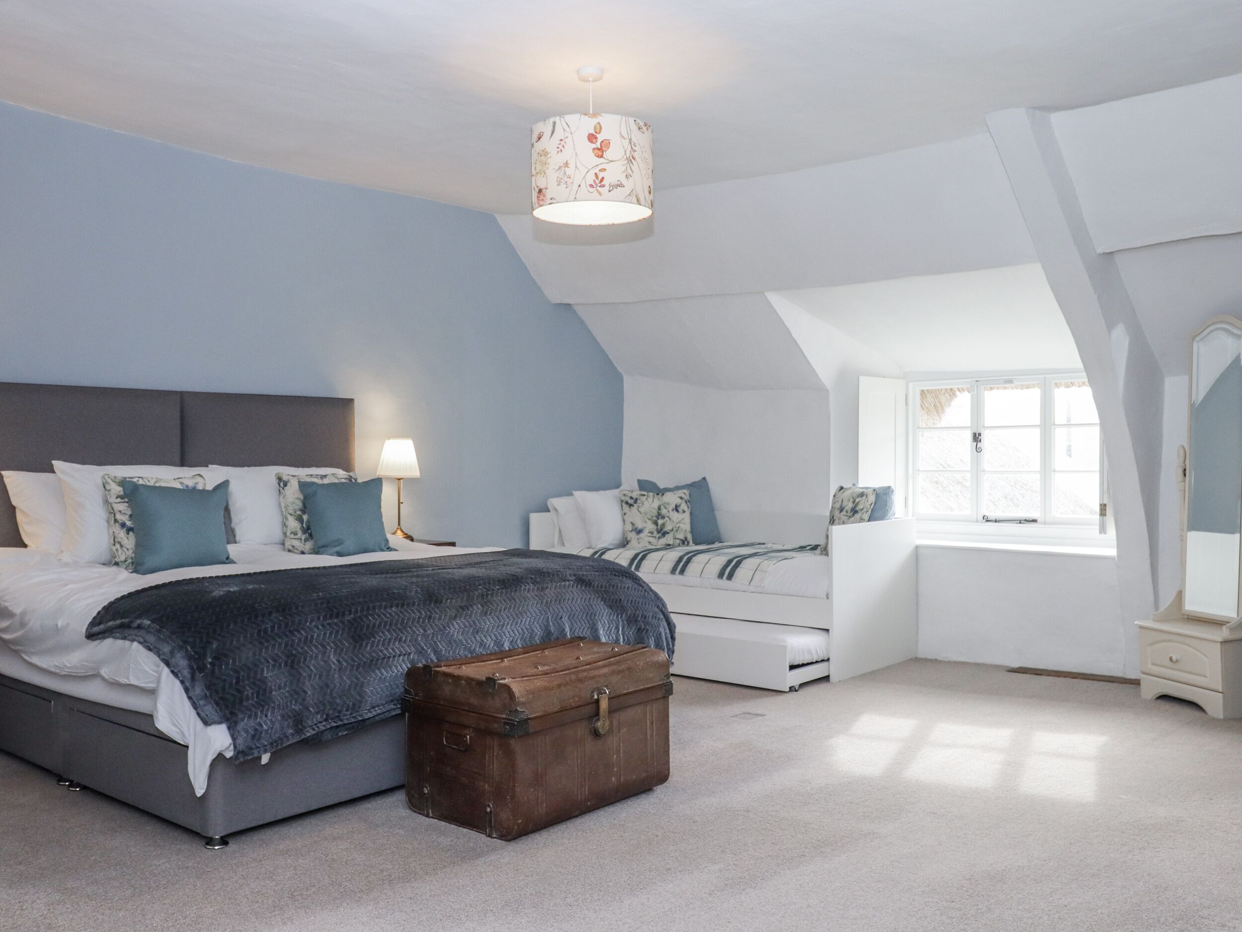 A bedroom with a bed, bedside tables, a suitcase, and a window.