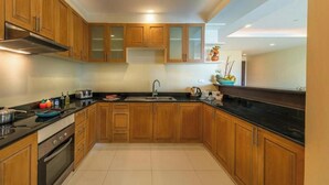 A kitchen with wooden cabinets, a black countertop, a stove, and a sink.