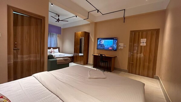 A hotel room with a large bed, a desk, a television, and a wardrobe.