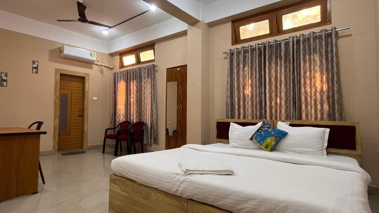 A bedroom with a bed, a desk, a chair, and a ceiling fan.