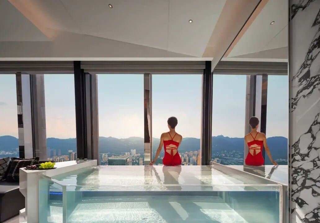 A modern interior with a large glass pool and a city view.