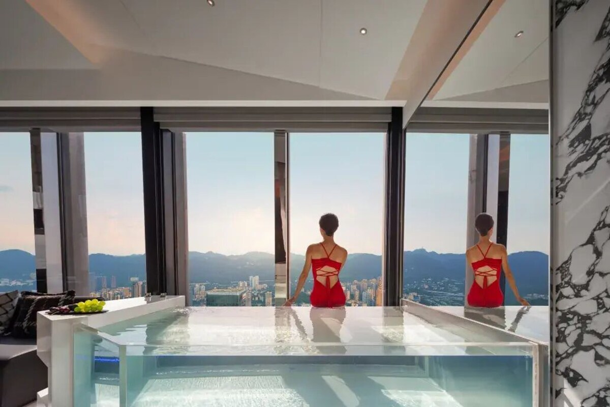 A modern interior with a large glass pool and a city view.