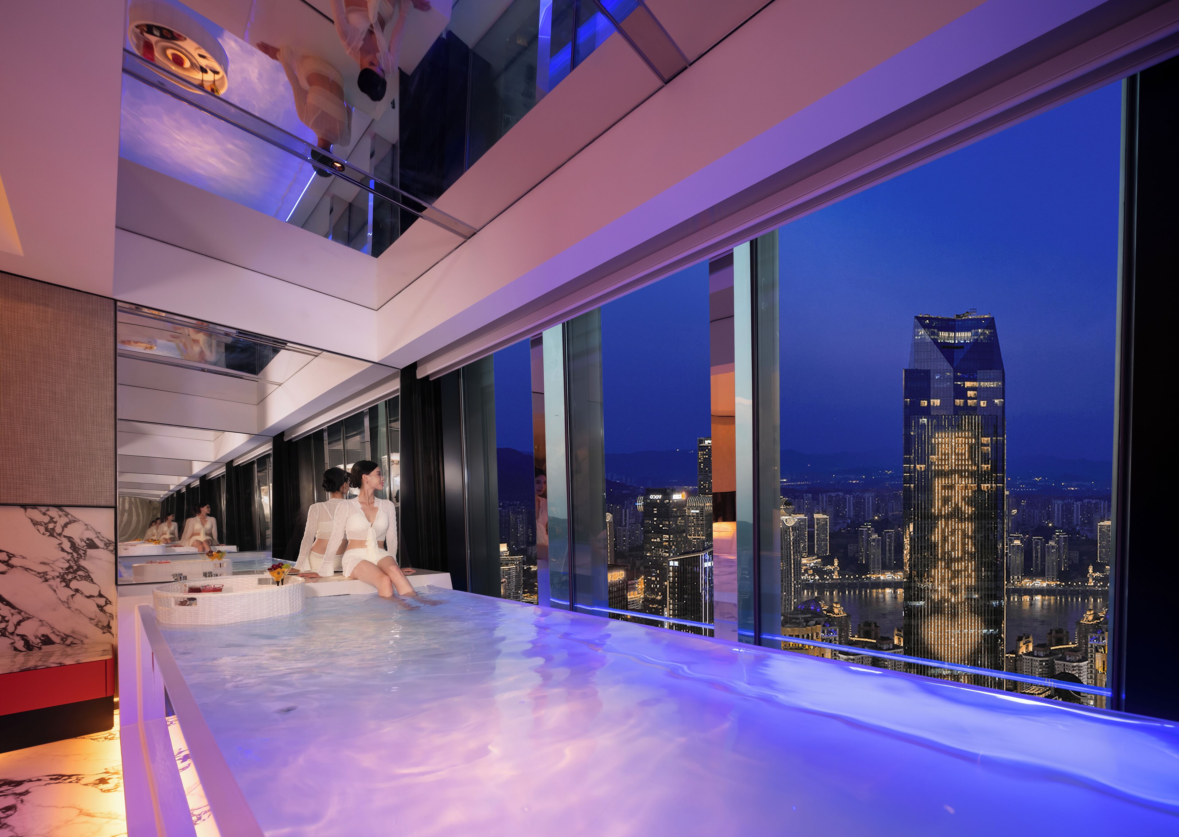 A modern hotel room with a city view, a large window, and a seating area by the window.