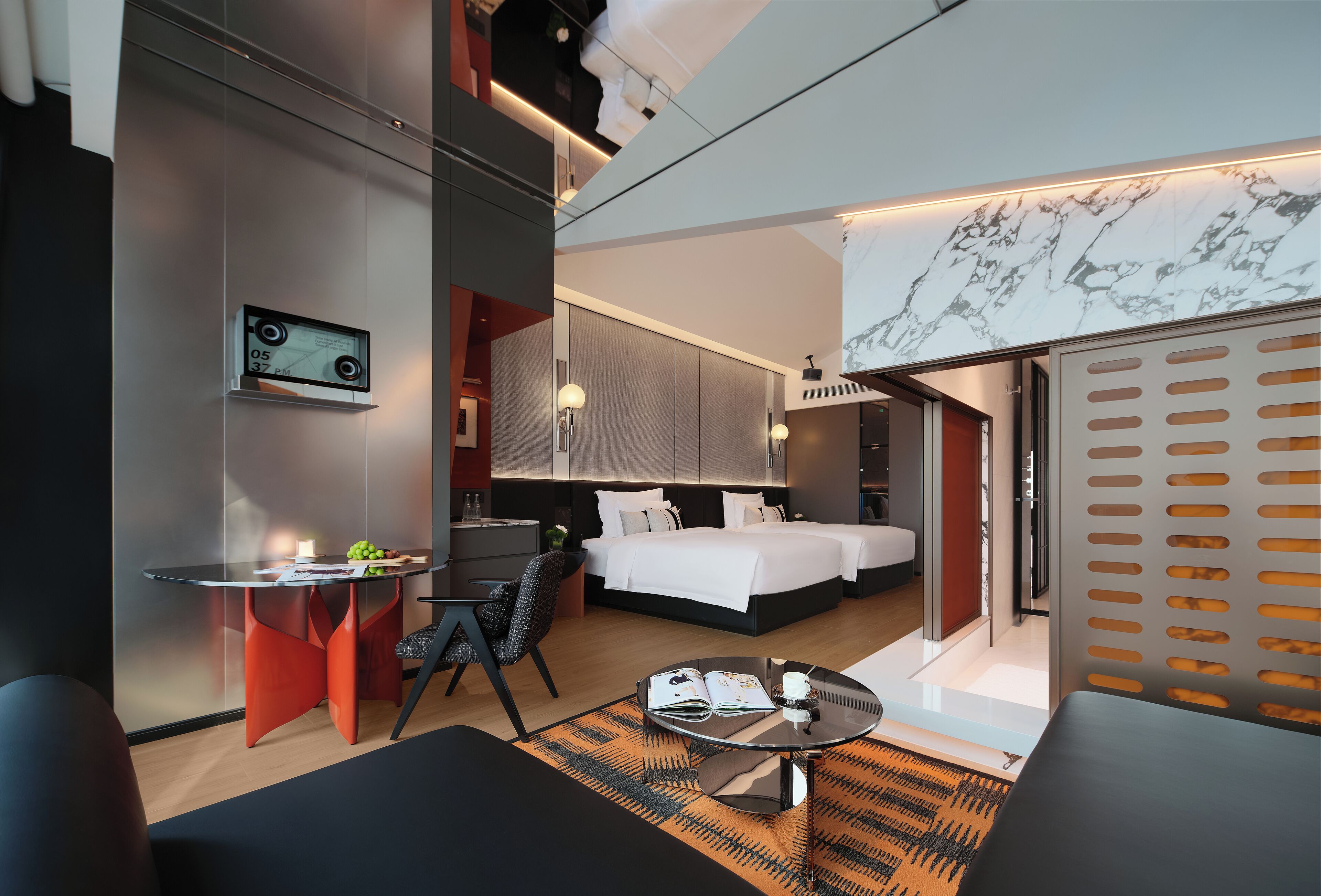 Una habitación de hotel moderna con cama, escritorio, silla, pequeña mesa y sofá.