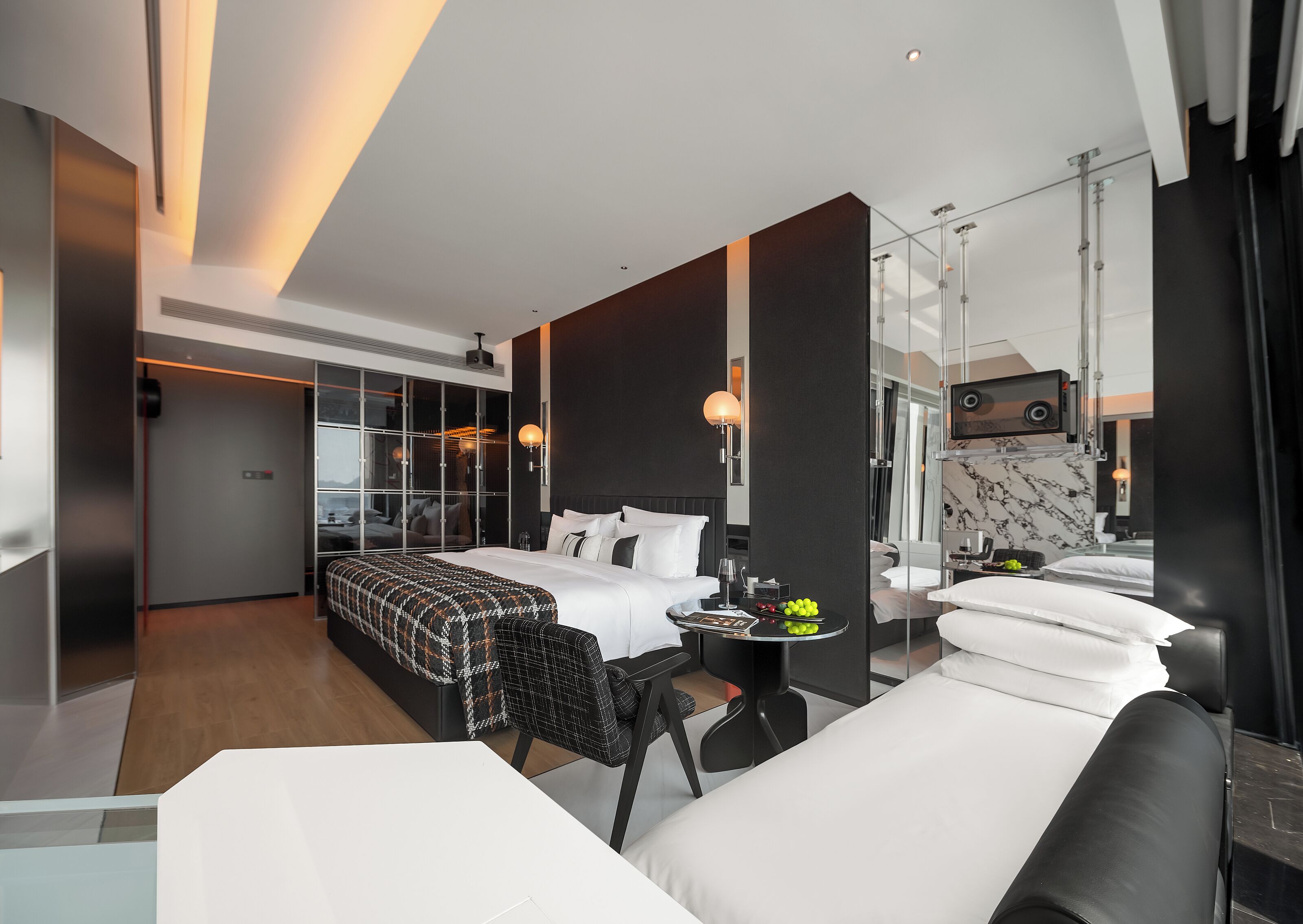 A modern hotel room with a large bed, a desk, and a seating area.