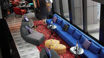 A modern lounge with a blue sofa, red armchairs, and a patterned rug.