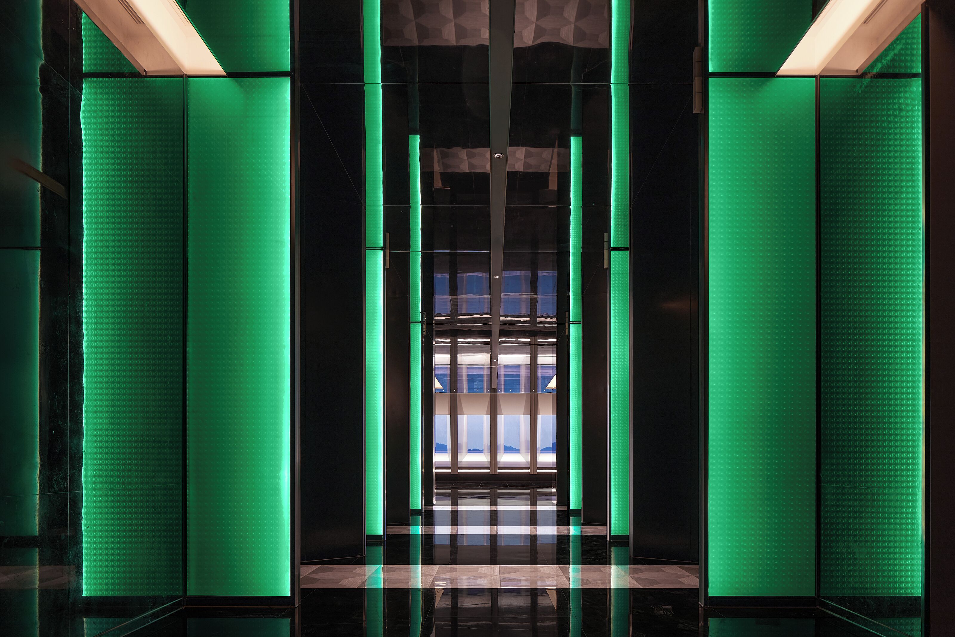 A modern elevator with green lighting and a reflective floor.
