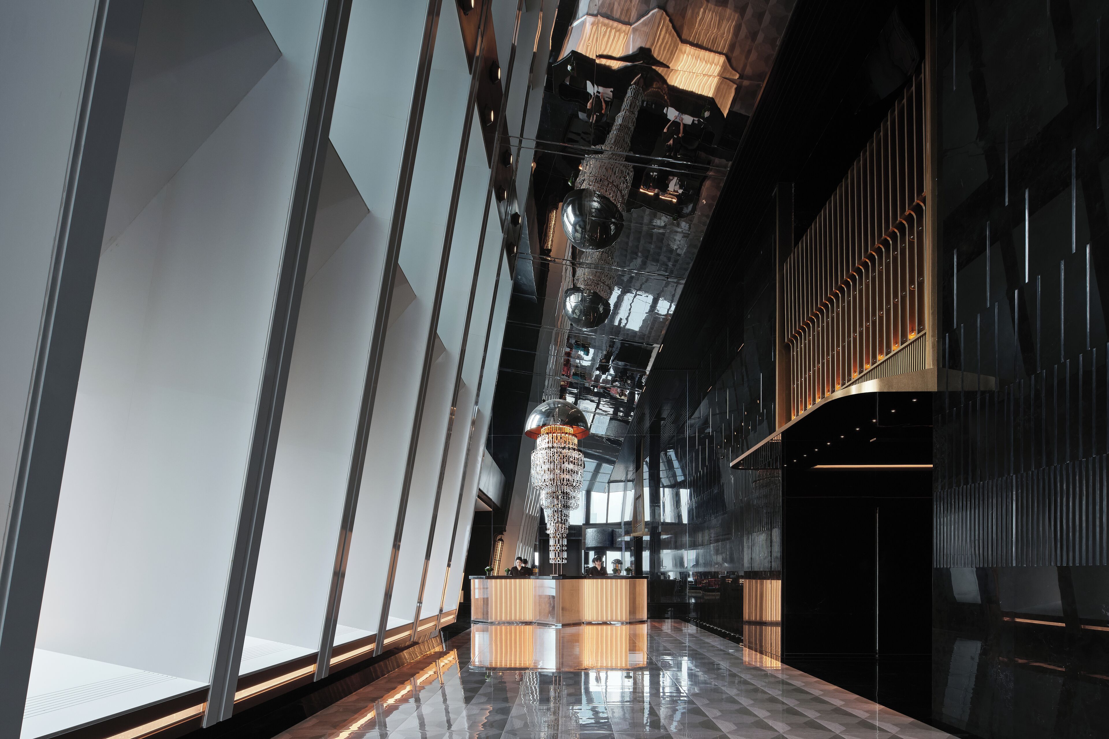A modern lobby with a reception desk, reflective floor, and geometric ceiling design.