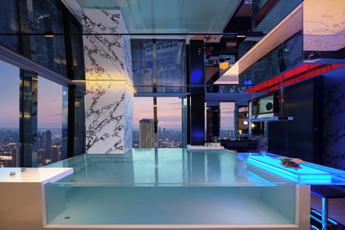 A modern interior with a glass pool, marble walls, and a city view.