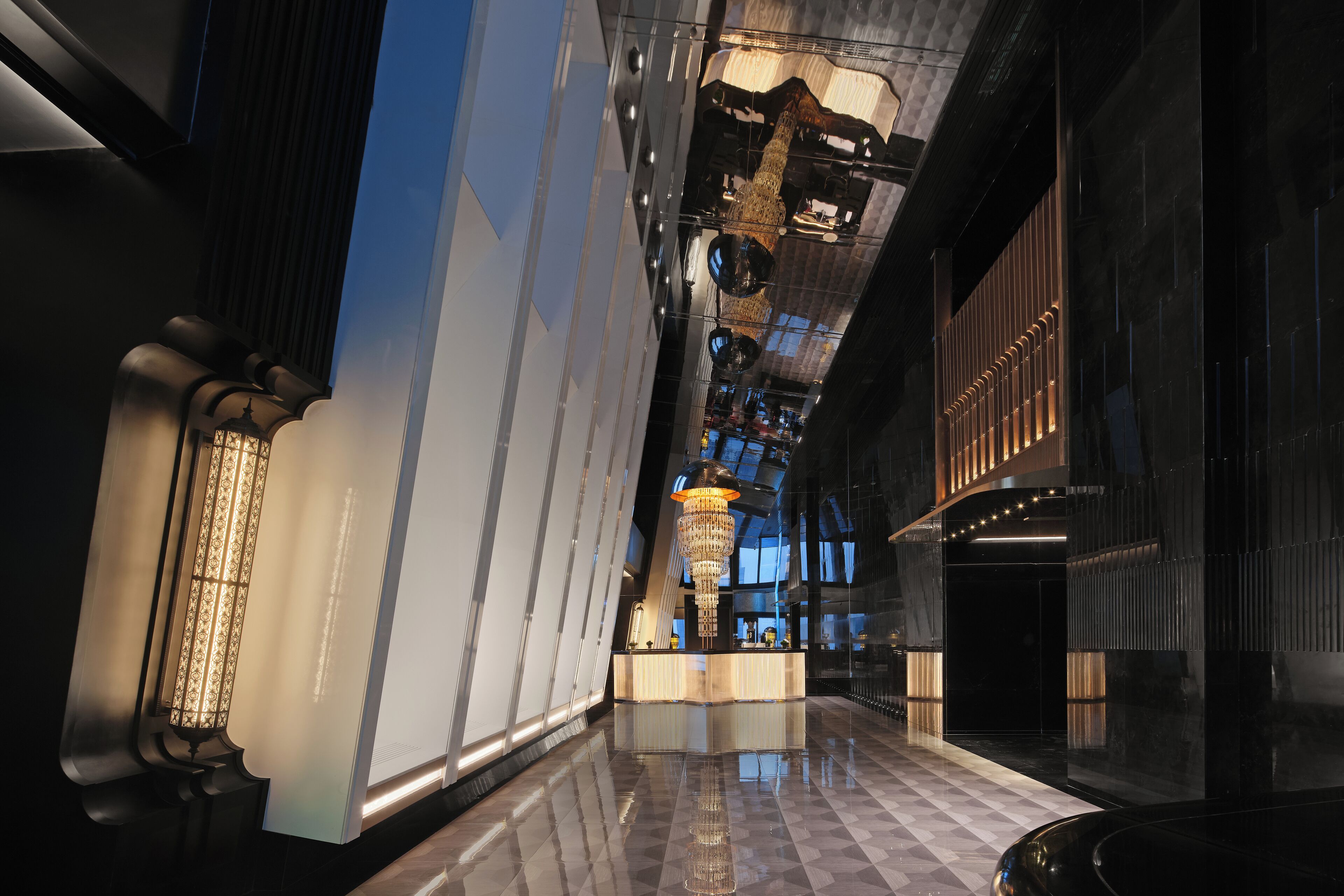Eine moderne Lobby mit einer zentralen Rezeption, einem Chandelier und einem Schachbrettmuster-Boden.