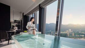 Un intérieur moderne avec une piscine à débordement en verre, une vue sur la ville et un espace cuisine.