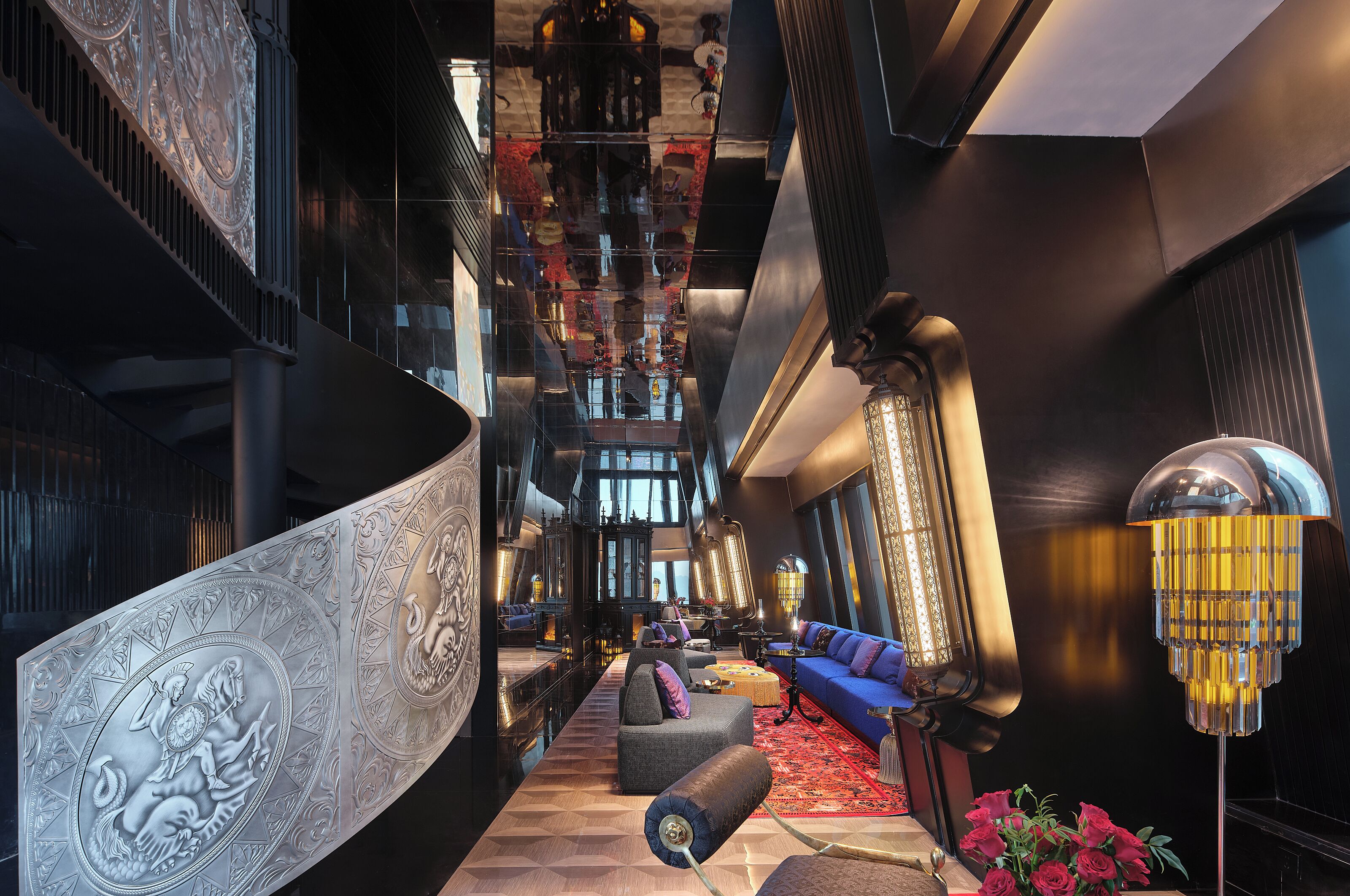 Eine geräumige Lobby mit einer imposanten Treppe, einer Sitzecke mit Sofas und einer dekorativen Wand.