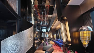 Eine geräumige Lobby mit einer imposanten Treppe, einer Sitzecke mit Sofas und einer dekorativen Wand.