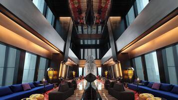 A spacious lobby with a central chandelier, sofas, and a patterned floor.