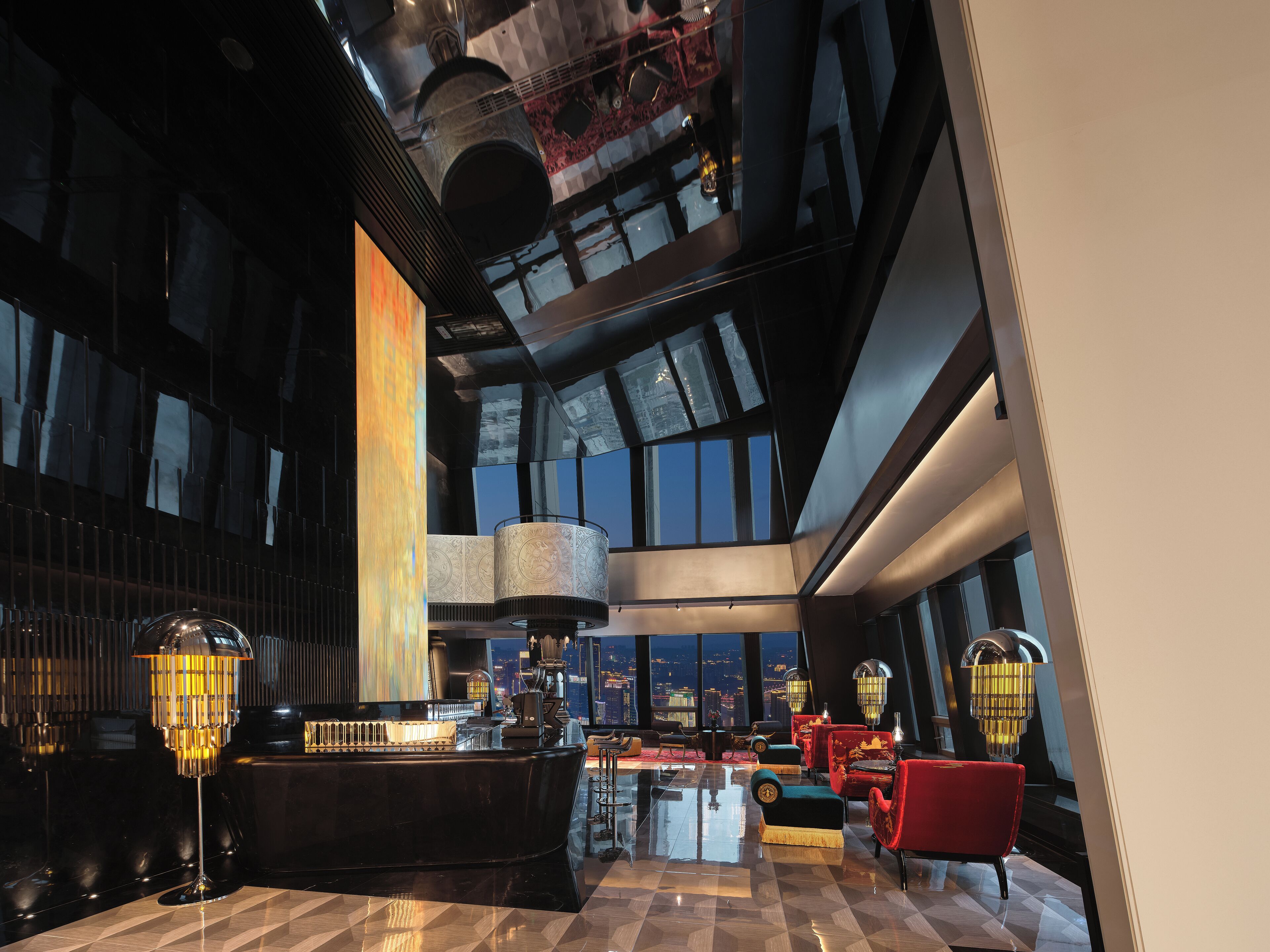 A spacious lobby with a grand piano, red upholstered seating, and large windows offering a city view.