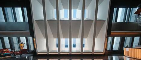 A modern hotel lobby with a central reflective floor, large windows, and a reception desk.