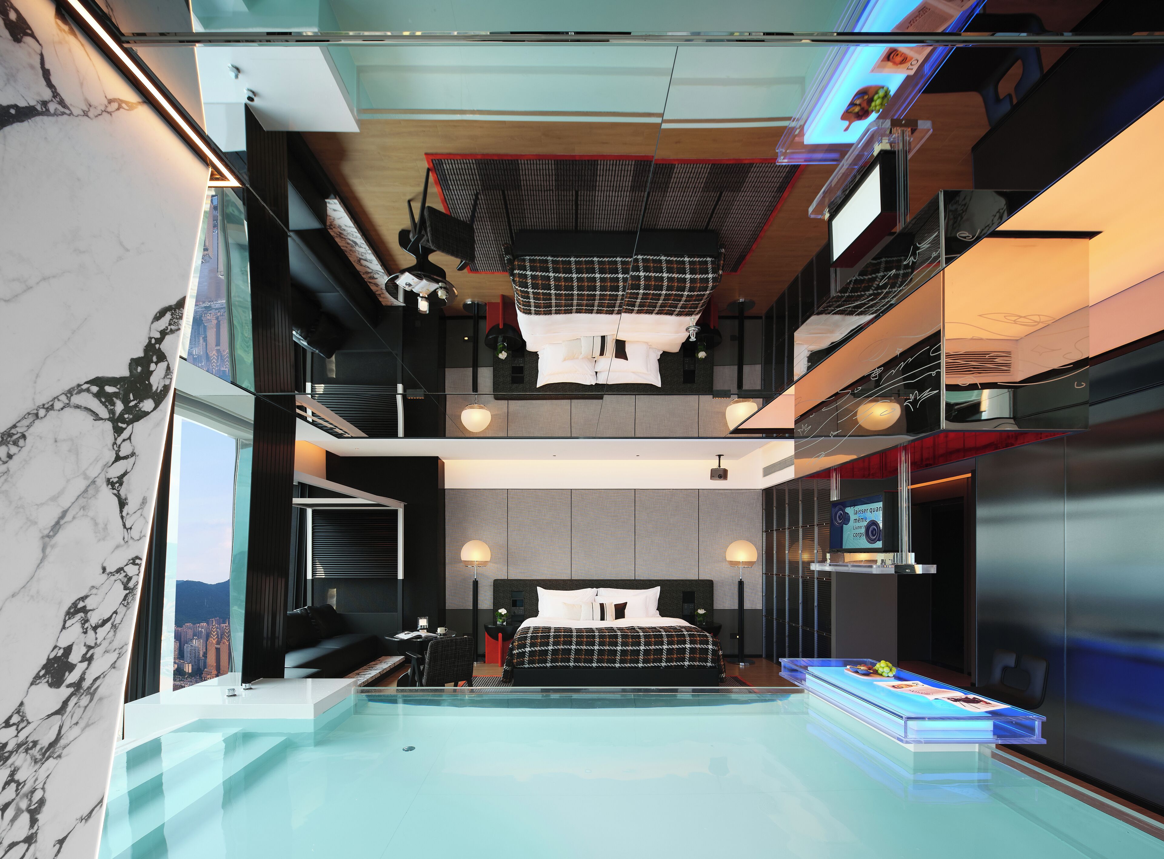 Una habitación de hotel moderna con una cama grande, un escritorio, una silla, una mesita y una zona de piscina.