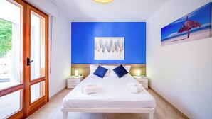 A hotel room with a large bed, two bedside tables, a painting on the wall, and a view through a large window. - Marina Beach Apartments (Alcamo)